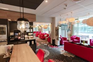 シュヴェービッシュ・ハルにあるqubixx stadtmittehotelの赤い椅子とテーブルが置かれたサロンの部屋