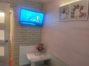 a room with a tv and a table with flowers at Pokój dla jednej osoby z łazienką in Gniezno