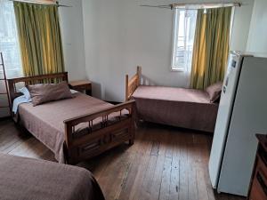 a bedroom with two beds and a refrigerator at Hostal Puerto Lounge in Valparaíso