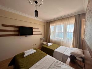 una camera d'albergo con due letti e una TV a schermo piatto di cunda panorama otel a Ayvalık