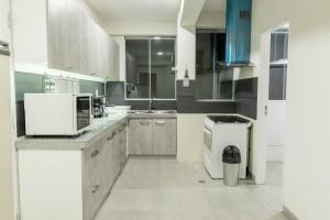 a large kitchen with white cabinets and a microwave at Tower Center Apartment in La Paz +11 photos