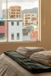two stacks of towels sitting on a bed in front of a window at Tower Center Apartment in La Paz