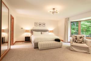 a white bedroom with a bed and a chair at Le Manoir 9 bedrooms Indoor Pool Walk to Resort in Mont-Tremblant +64 photos