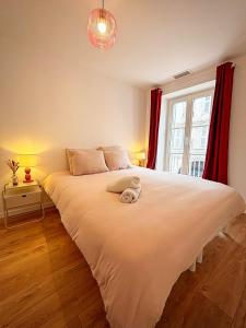 a bedroom with a large white bed with red curtains at Joli Perot in La Rochelle