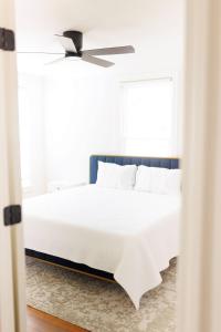 een slaapkamer met een wit bed met een plafondventilator bij Cozy Historic District Cottage in Dothan +14 foto's