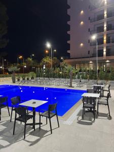 un gruppo di tavoli e sedie accanto a una piscina di notte di Hotel Antik a Golem