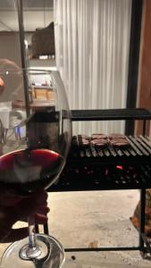 un bicchiere di vino rosso seduto accanto a una griglia di Casa Arcanjo - Patacho a Pôrto de Pedras