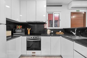 eine weiße Küche mit weißen Schränken und einer Mikrowelle in der Unterkunft River Side in Senhora do Rosário + 21 Fotos