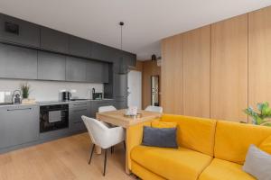a living room with a yellow couch and a table at Fuzja w Chmurach - parking, klimatyzacja by FusionAparts in Łódź