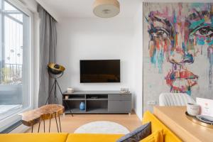 a living room with a television and a painting on the wall at Fuzja w Chmurach - parking, klimatyzacja by FusionAparts in Łódź