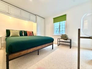 a bedroom with a bed with green sheets and a window at Seafront Flat By Mrs Butler Short Term Rental Brighton in Brighton & Hove