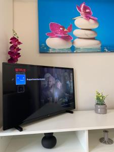 a flat screen tv sitting on top of a white table at F K Apartments in Artemida