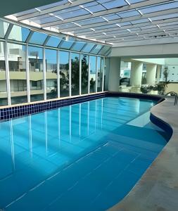 een groot zwembad in een gebouw met ramen bij Flat ao lado do Mar Four Season in Guarujá