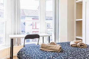 リバプールにあるFree Parking, 4 Bed, 2 Bath House, Long Term Stay Savings, Contractors, Near Anfieldのベッドとテーブル、タオルが置かれた部屋