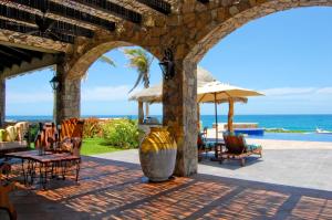 a patio with chairs and an umbrella and the ocean at Villa Estero by Cabo Villas in San José del Cabo