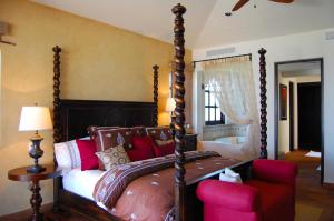 a bedroom with a canopy bed and a red chair at Villa Estero by Cabo Villas in San José del Cabo