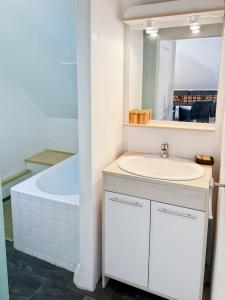 a white bathroom with a sink and a tub at La maison Hortensias Vic-Sur-Cère - 6pers in Vic-sur-Cère