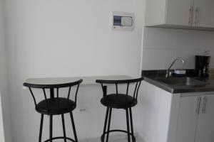 a kitchen with two black bar stools and a sink at Apartaestudio Increible in Valledupar