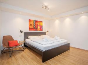 een slaapkamer met een bed en een stoel en een schilderij bij Moderne stilvolle Wohnung im Herzen Münchens in München