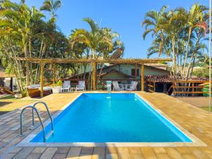 a pool with a wooden deck and a house with palm trees at Pousada Sonho de Geribá in Búzios