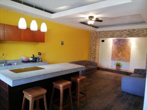 a kitchen with yellow walls and a bar with stools at Amplios y cómodos apartamentos en Playa del Carmen in Playa del Carmen