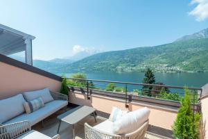 Un balcón con sofá y sillas y vista a un lago. en Lake View Apt - Only 15 min to Trento, en Vignola