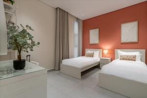 twee bedden in een kamer met oranje muur bij 3BR Luxury Stay in Riyad +26 foto's