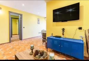 a living room with a blue cabinet and a tv on a yellow wall at Charming Coastal Retreat in Alboraya