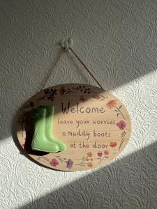Un cartel colgado en una pared con un cartel de bota verde. en Clover Cottage, Tenby, en Tenby