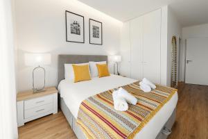 Un dormitorio blanco con una cama grande con toallas. en Beautiful Sunset Views, en Nazaré