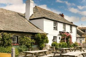 a white building with picnic tables in front of it at Shepherds Huts at The Cornish Arms in St Merryn