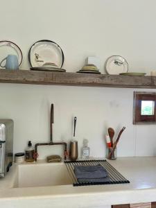 Un fregadero de cocina con platos y utensilios en un estante. en El Nido, Riad San Cristobal, en Troncones