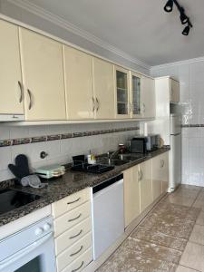 a kitchen with white cabinets and white appliances at Sea and Nature Escape in Furadouro