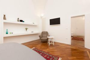 um quarto branco com uma cadeira e uma televisão em San Matteo House em Lecce