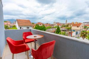 a balcony with red chairs and a table with a view at Hotel Shkodra Comfort in Shkodër