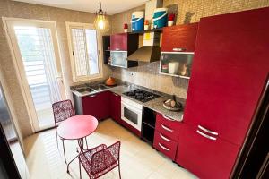 a kitchen with red cabinets and a table and chairs at Amazing Stylish Apt with Pool in Agadir