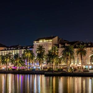a building with palm trees in front of a body of water at Apartment Sandra with balcony in Split +4 photos
