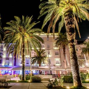 two palm trees in front of a building at night at Apartment Sandra with balcony in Split