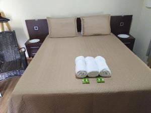 a bed with three rolled up towels on it at Chalé Portal Lazer Propriedade Inteira in Gonçalves