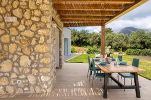 a wooden table and chairs on a patio with a stone wall at Villa Manù country house in Castellammare del Golfo