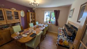 a dining room with a long table with green chairs at Willowdale B&B in Breakish
