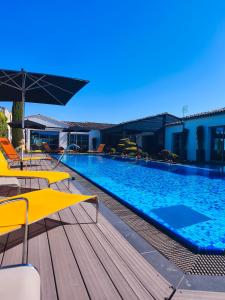 a swimming pool with chairs and umbrellas next to a building at ღ Villa des Astres 850 m2 - Piscine, Sauna, Hammam, & Salle de Cinéma in La Noue