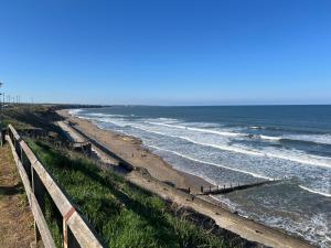 a beach with a fence next to the ocean at Seaham Apartment GO69OOD Ltd in Seaham