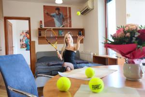 巴拉顿菲赖德Roger Federer apartmanja的一位女士坐在床上，手里拿着网球拍