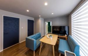 a living room with blue chairs and a table and a television at Rental Whole House Sakaemachi in Furano