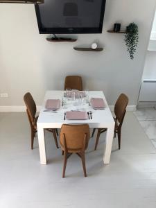 a white dining room table with chairs and a tv at Fleur de coton - 7 lits in Clermont-Ferrand +14 photos