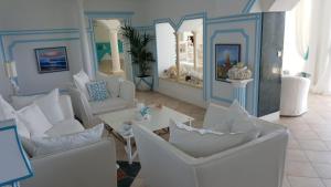 ein Wohnzimmer mit weißen Stühlen und einem Tisch in der Unterkunft Hotel La Calanque in Cavalaire-sur-Mer