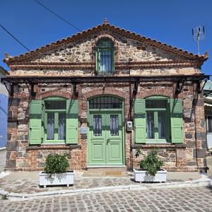 a brick building with green doors and windows at Petrino Guesthouse I Central Mytilini Stay in Pámfylla