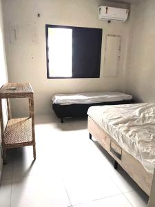 Una habitación con dos camas y una silla y una ventana. en APARTAMENTO Pe na Areia com piscina vista mar bairro nobre, en Bertioga