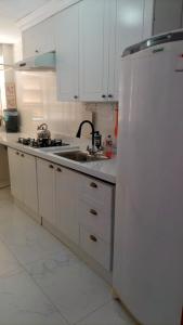 a white kitchen with a sink and a refrigerator at Apartamento completo no coração de Goiânia in Goiânia
